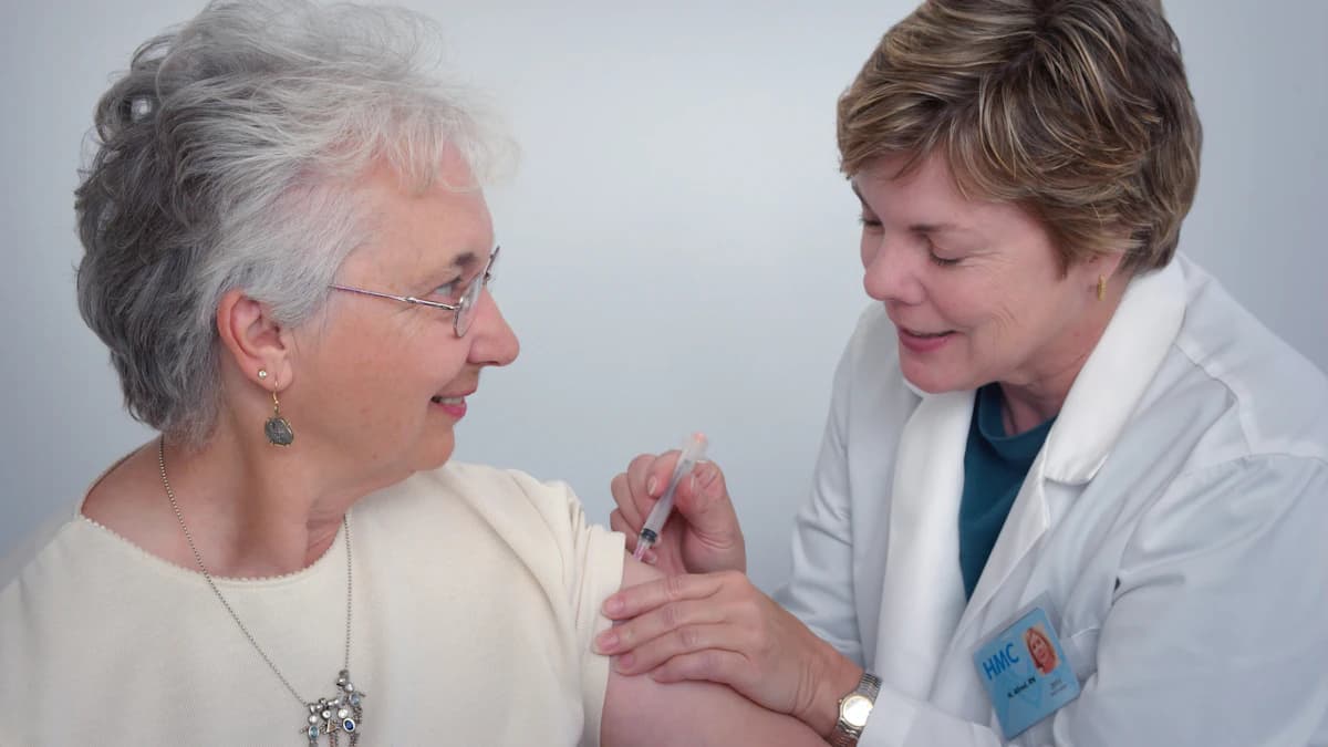 Wijkverpleegkundige bespreekt hulp bij medicatie thuis aan de keukentafel